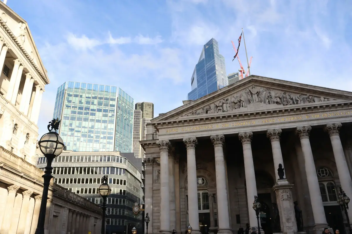 Stone portico of the Royal Exchange with glass office towers and a crane behind, City of London
