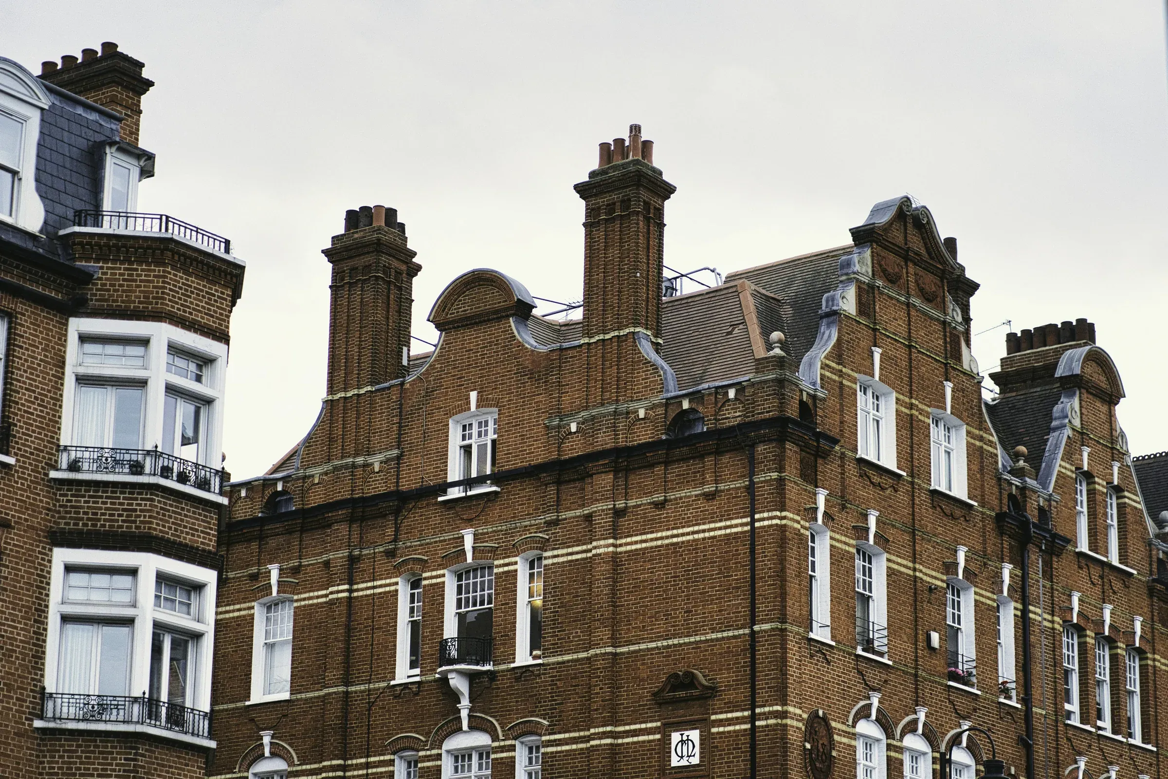Red-brick London mansion block with white sash windows and tall chimneys