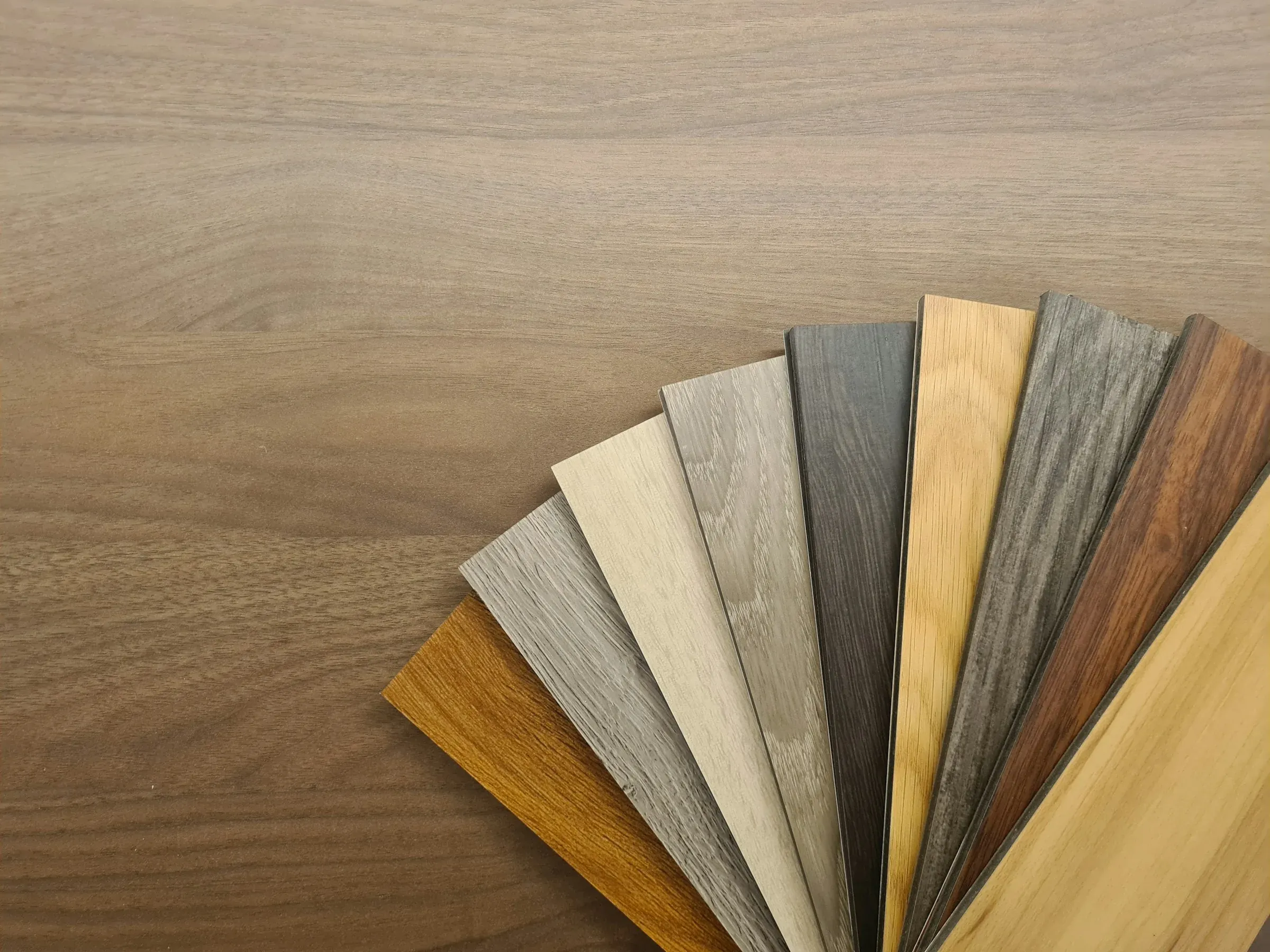 Fan of wood-effect flooring samples in different shades laid out on a timber table