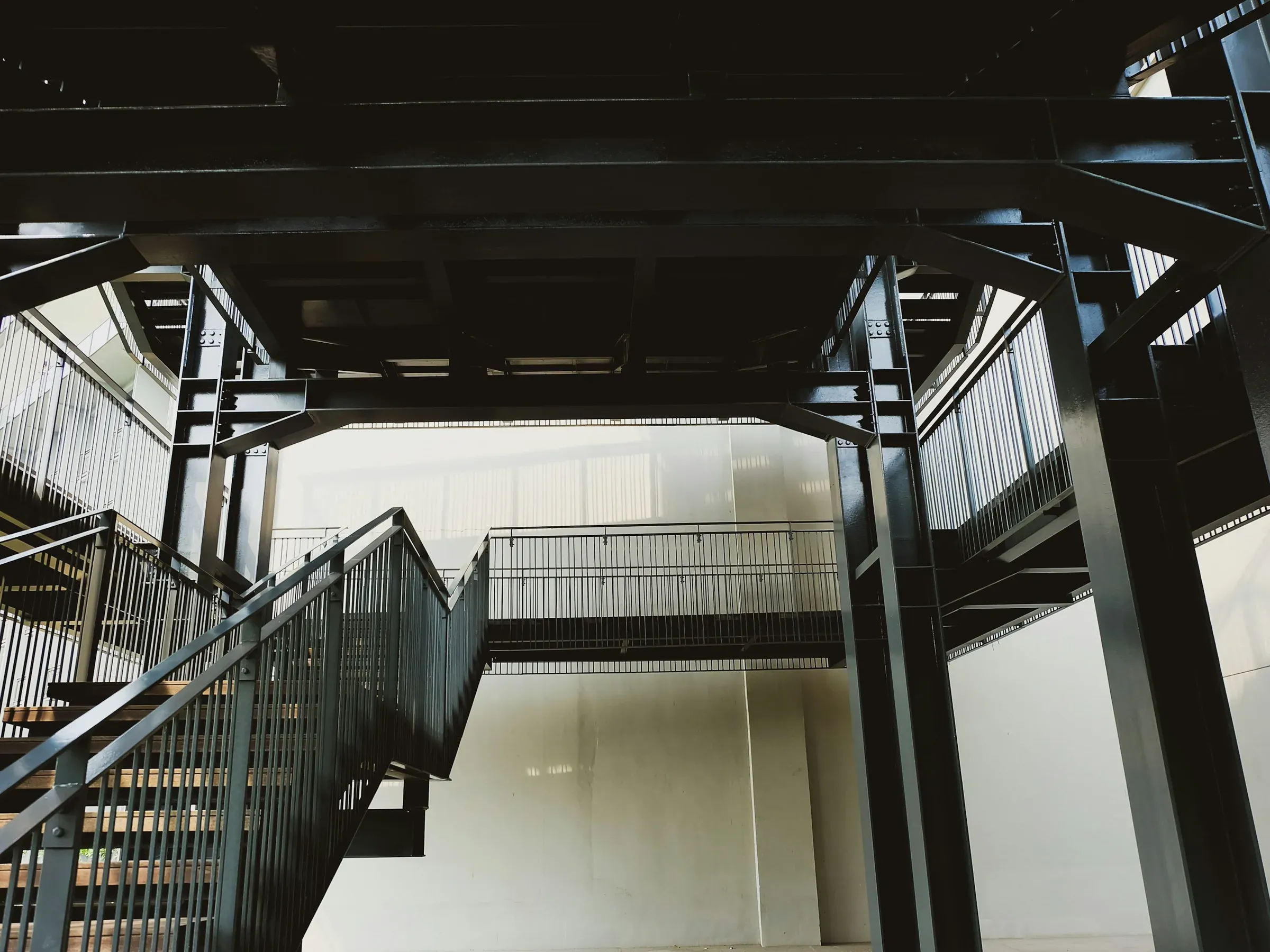 Black steel mezzanine deck with a staircase and railings inside a tall white building