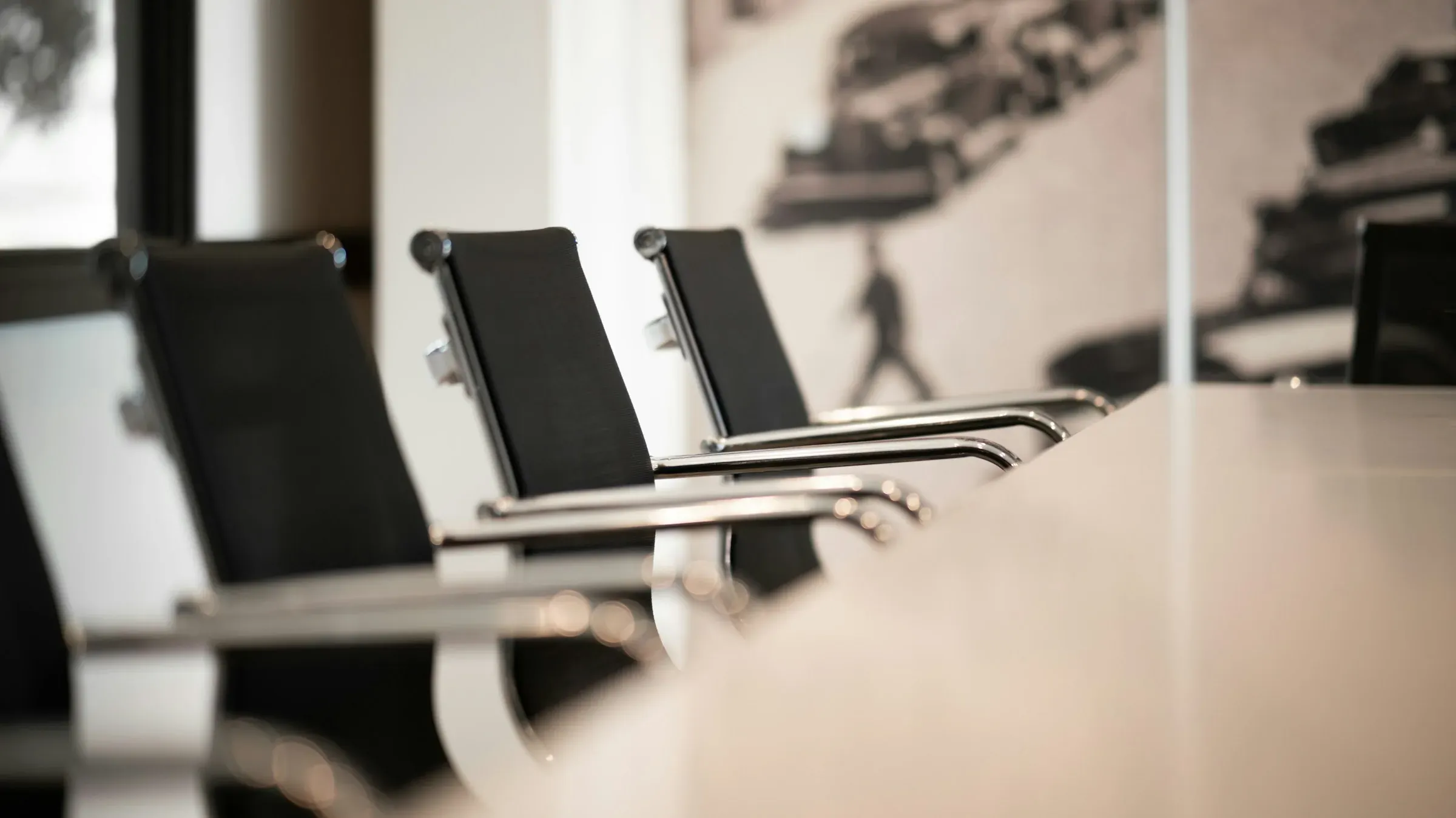Row of black office chairs at a white meeting table