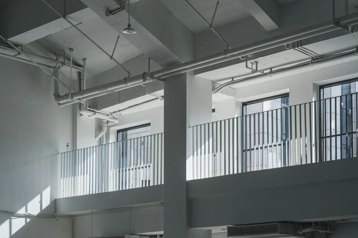 Stripped-back office space with exposed ceiling services, concrete columns and full-height glazing