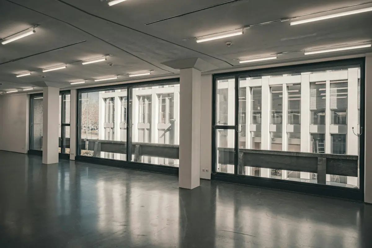 Vacant open-plan office floor with floor-to-ceiling windows, concrete columns and a polished floor