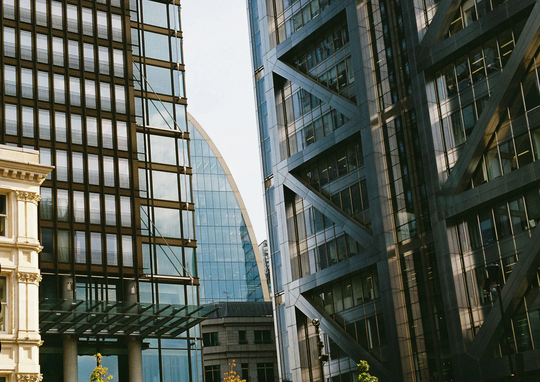 Glass and steel office facades with diagonal bracing beside a stone Victorian building in the City of London