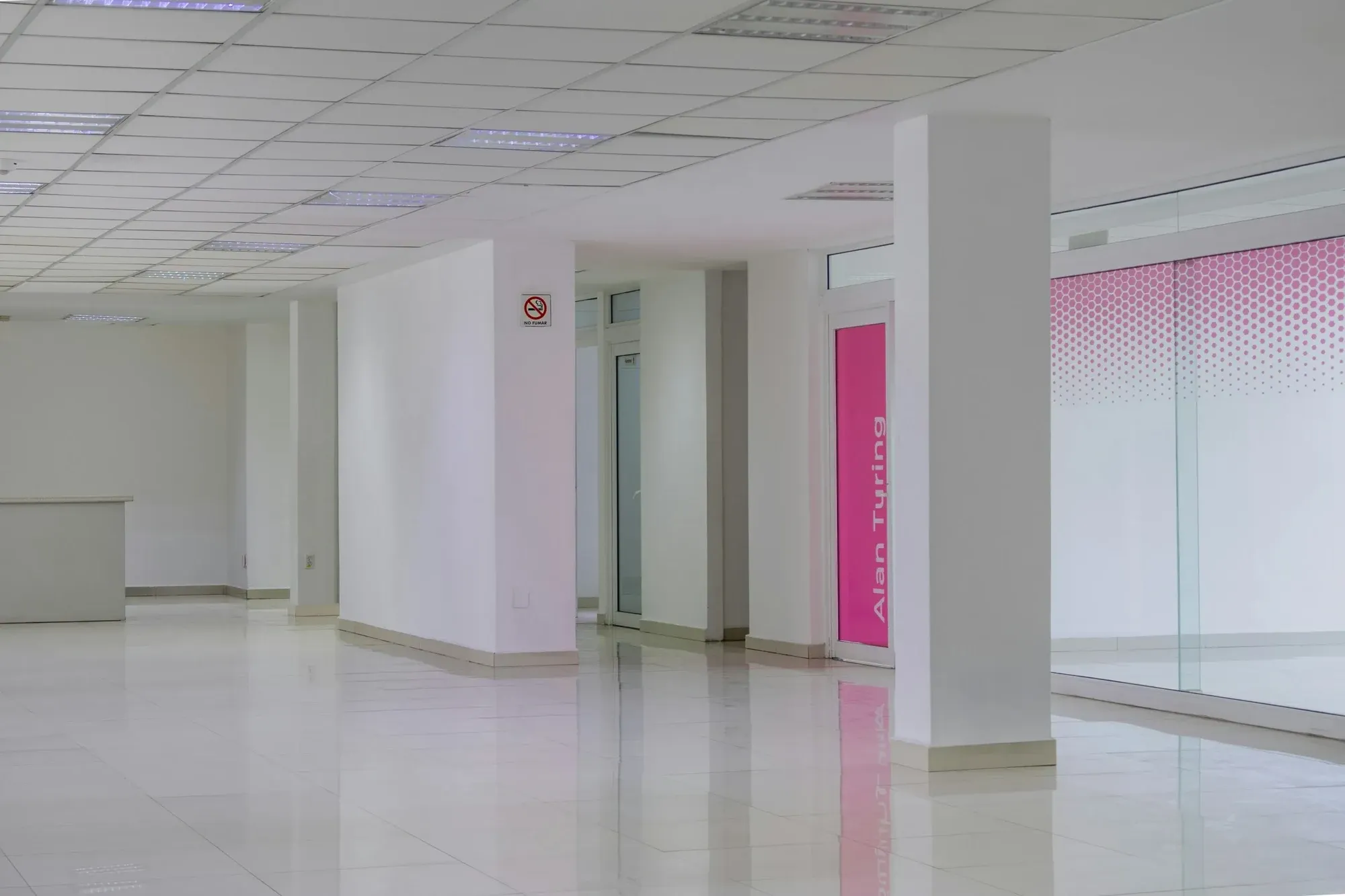 Empty open-plan office floor with white walls, glazed partitions and large windows