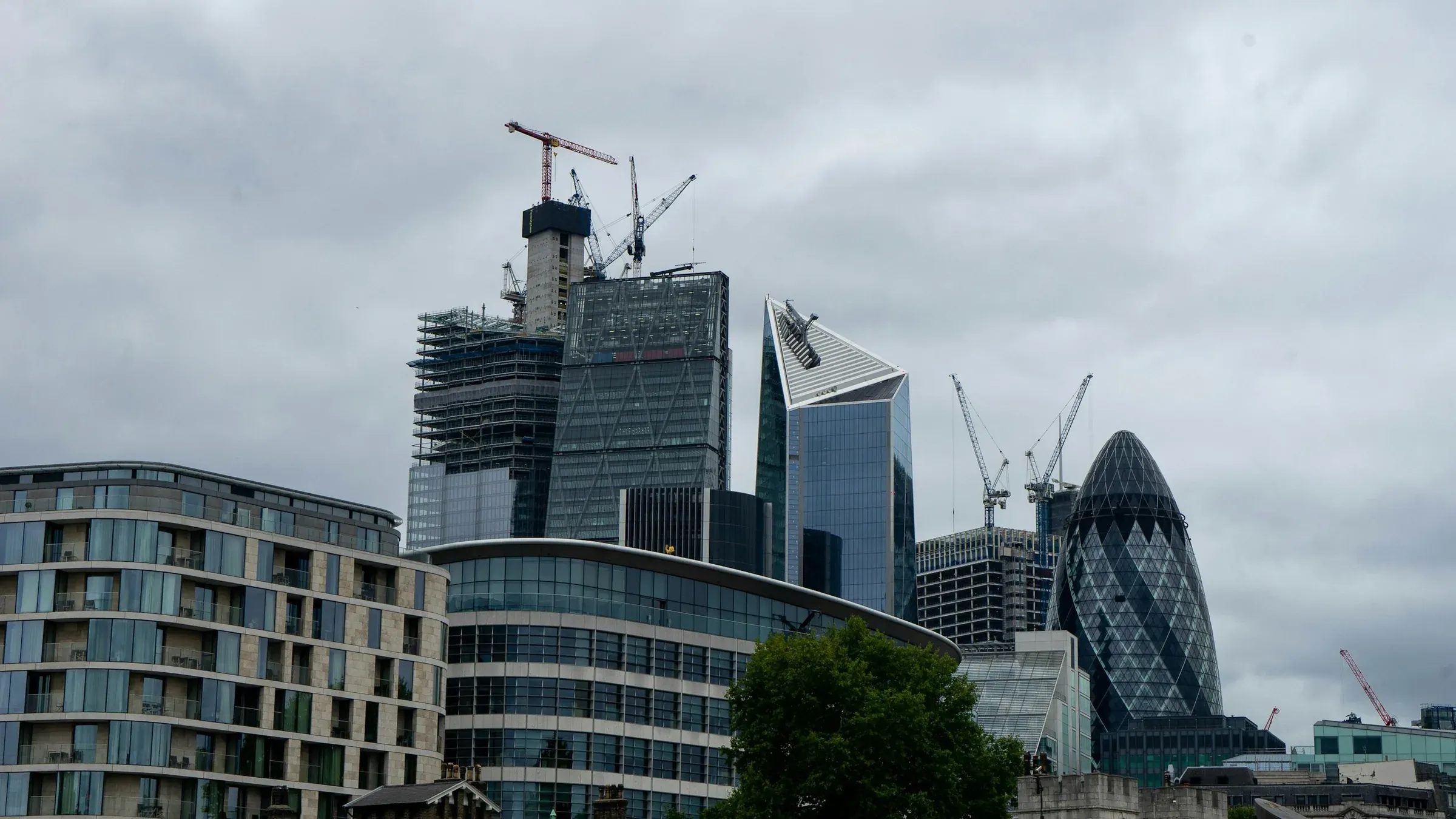 City of London towers seen from the Thames, with cranes over a tower under construction beside the Gherkin
