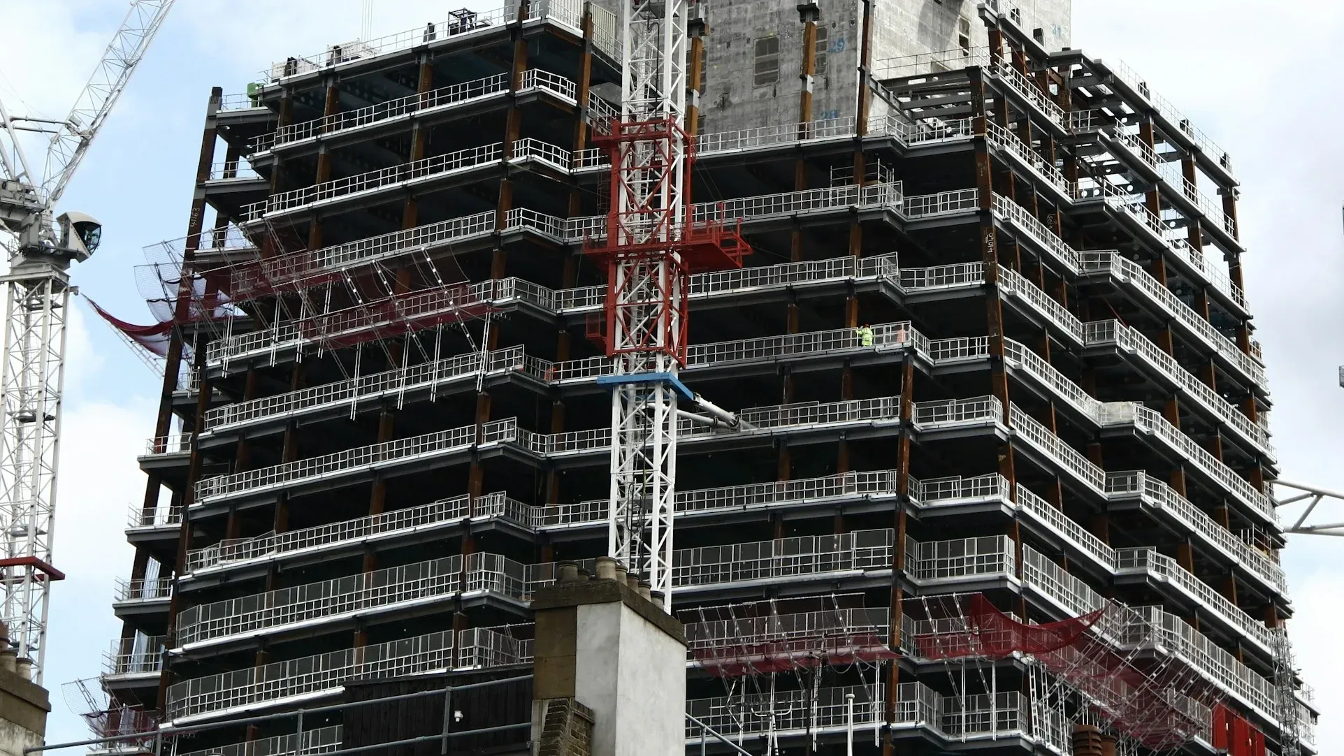 Concrete core and steel floors of a London tower under construction, with tower cranes on both sides