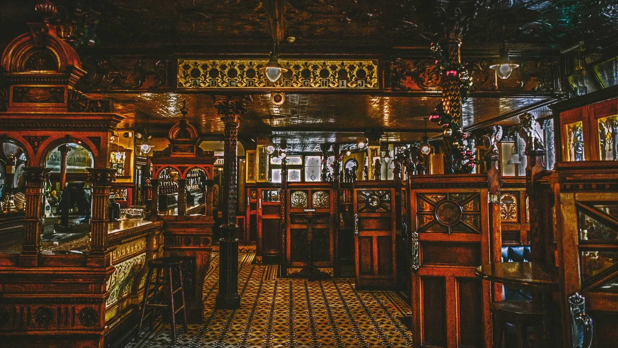 Victorian pub interior with carved timber snugs, a tiled floor and an ornate ceiling