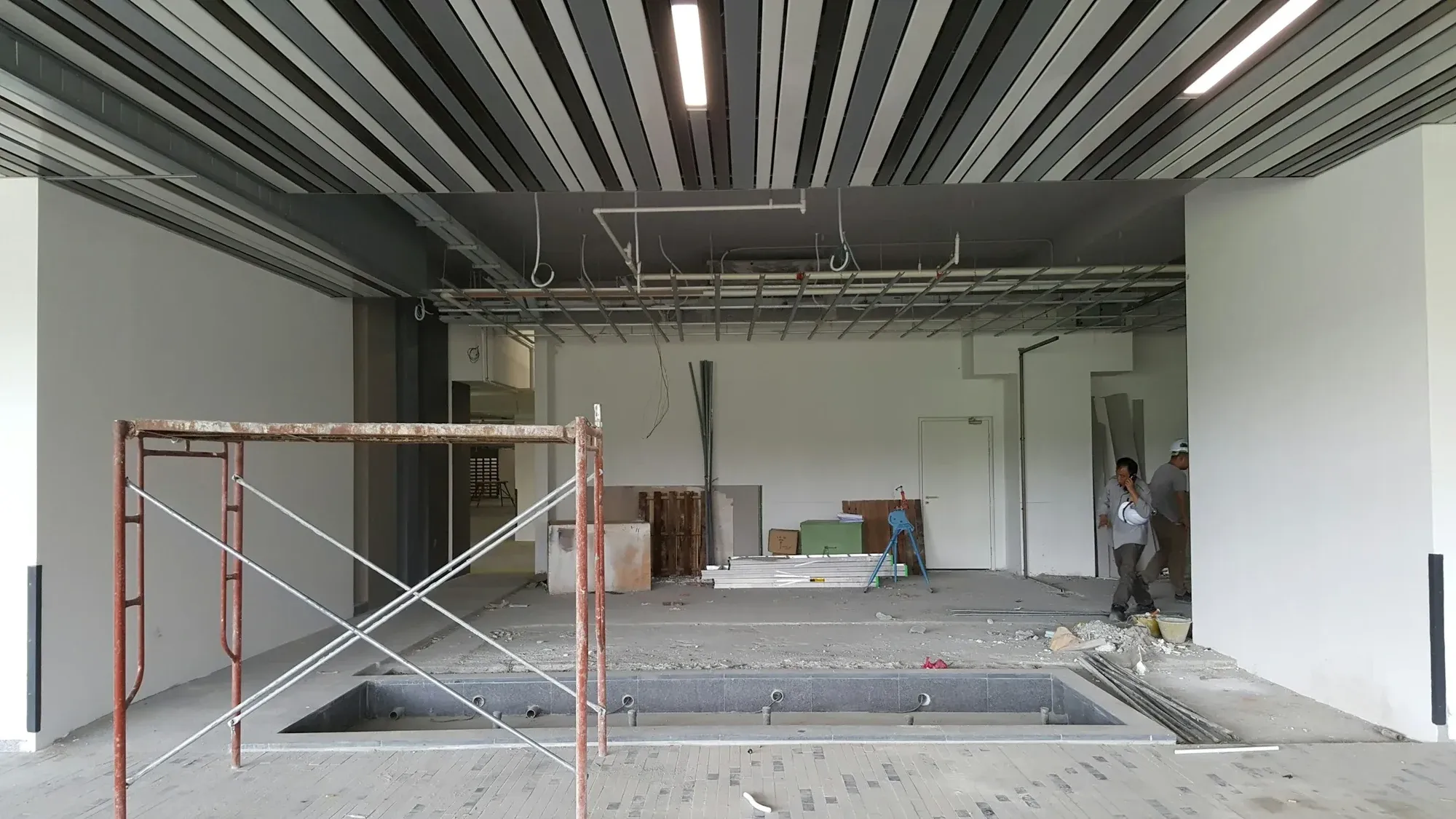 Open-plan floor stripped back for refurbishment, with a scaffold tower and exposed ceiling services