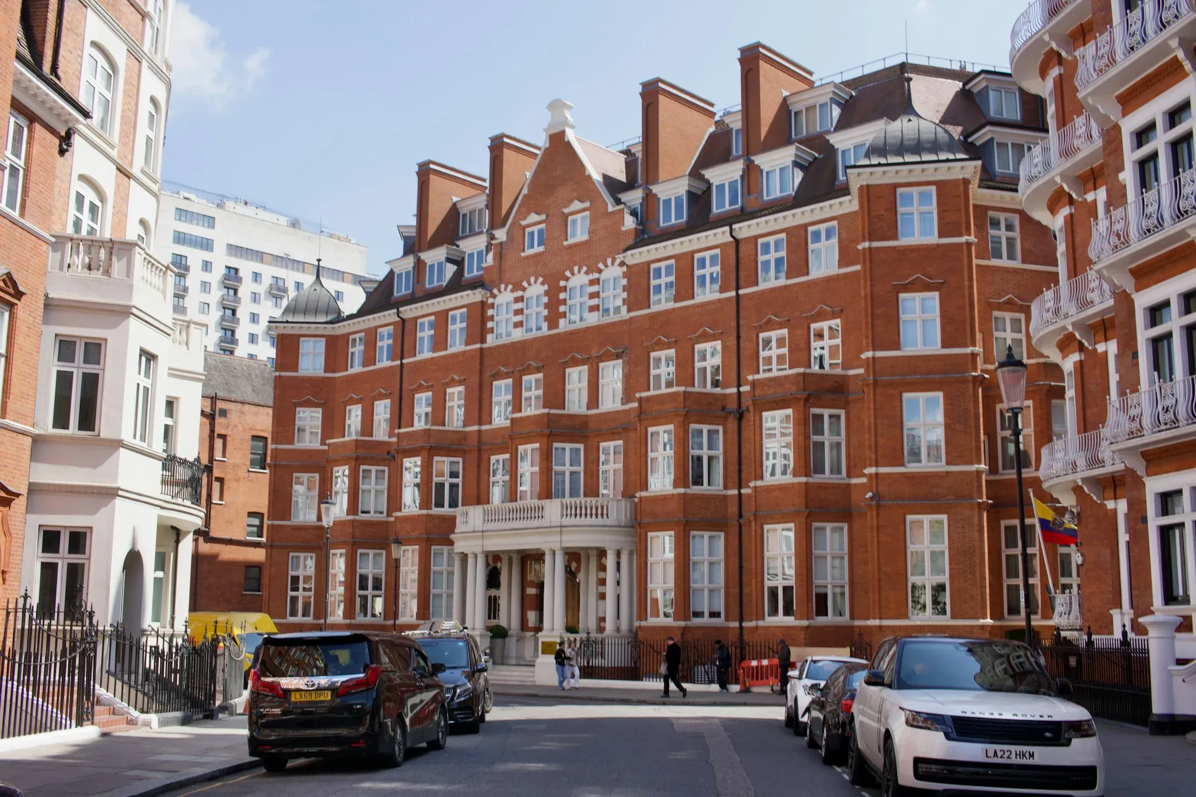 Red-brick London mansion block with ornate stone details on a residential street