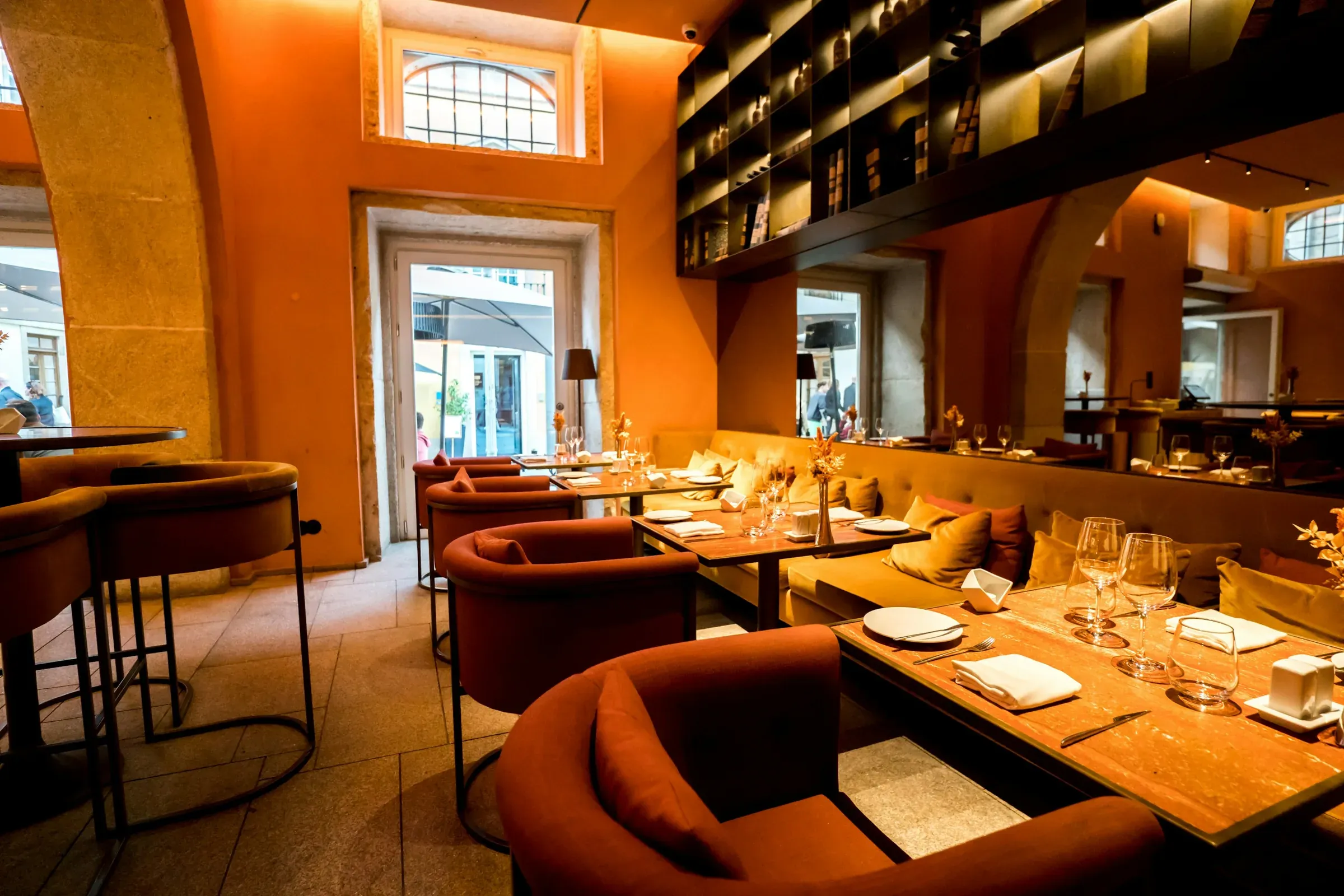 Restaurant dining room with terracotta walls, velvet tub chairs and a long banquette