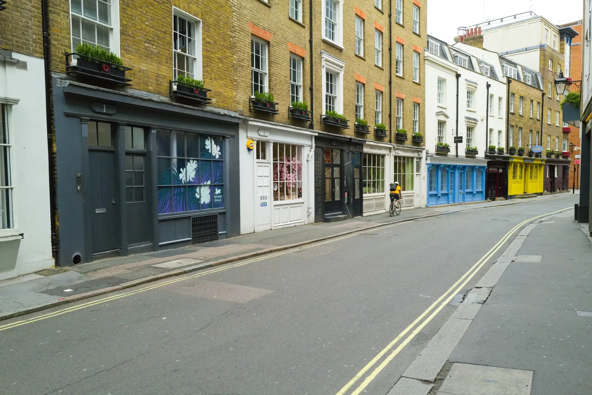 Row of painted shopfronts below brick upper floors on a quiet London street