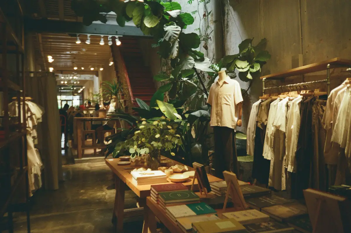 Boutique interior with timber display tables, clothing rails, track lighting and large plants