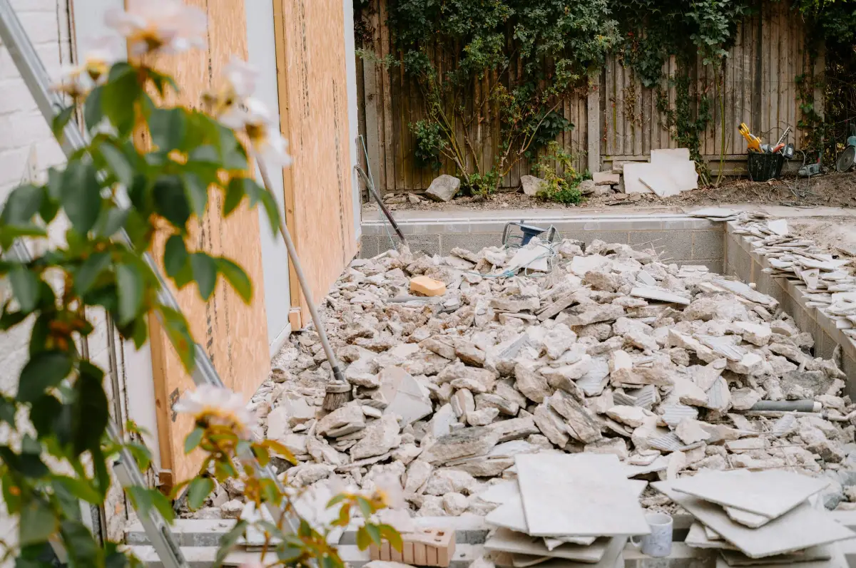 Back garden building site left with a pile of broken concrete rubble beside a boarded-up wall
