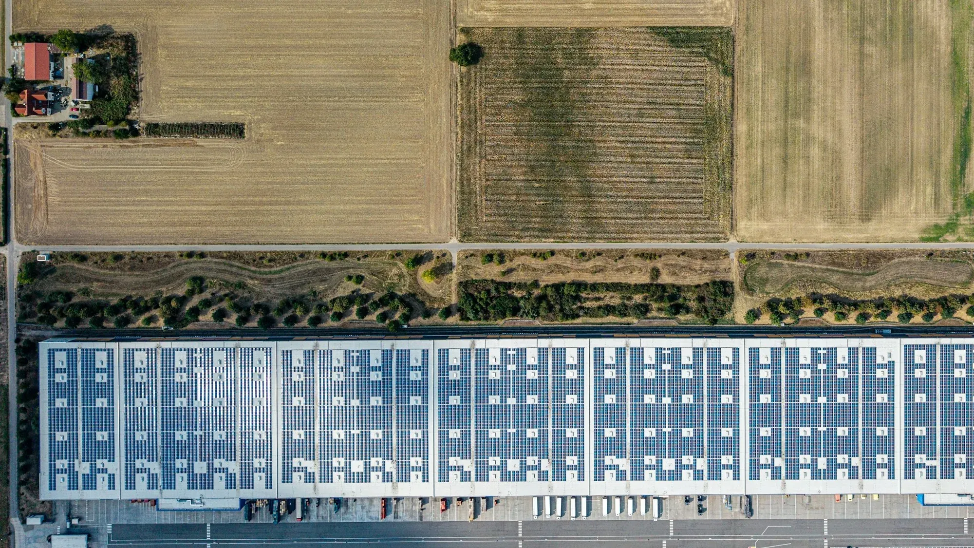 Aerial view of a long logistics warehouse roof fully covered in solar panels