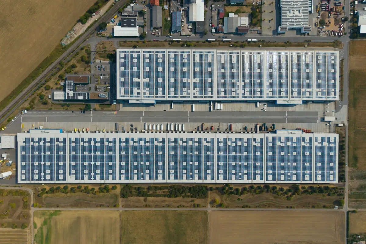 Aerial view of two large logistics warehouses with solar panels covering their roofs
