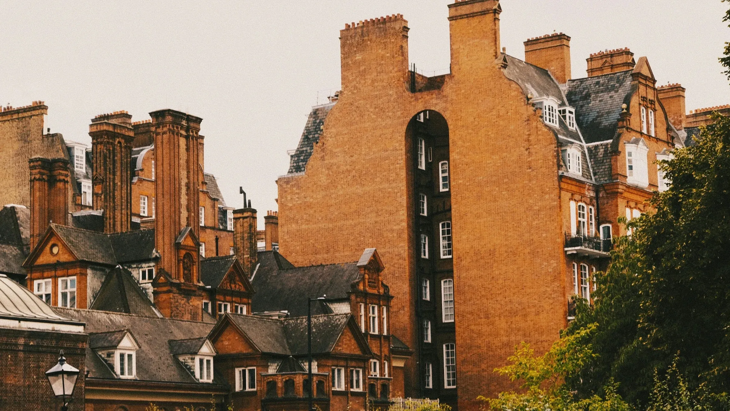 Red-brick Victorian mansion blocks with tall chimneys, gables and slate roofs in London