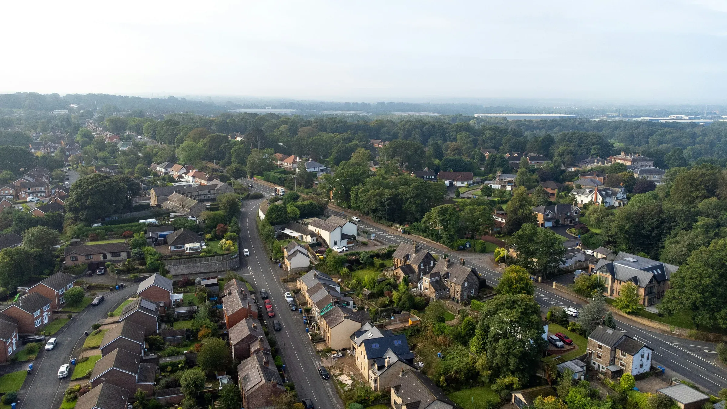 Aerial view of a leafy suburban neighbourhood with winding roads and detached houses in England