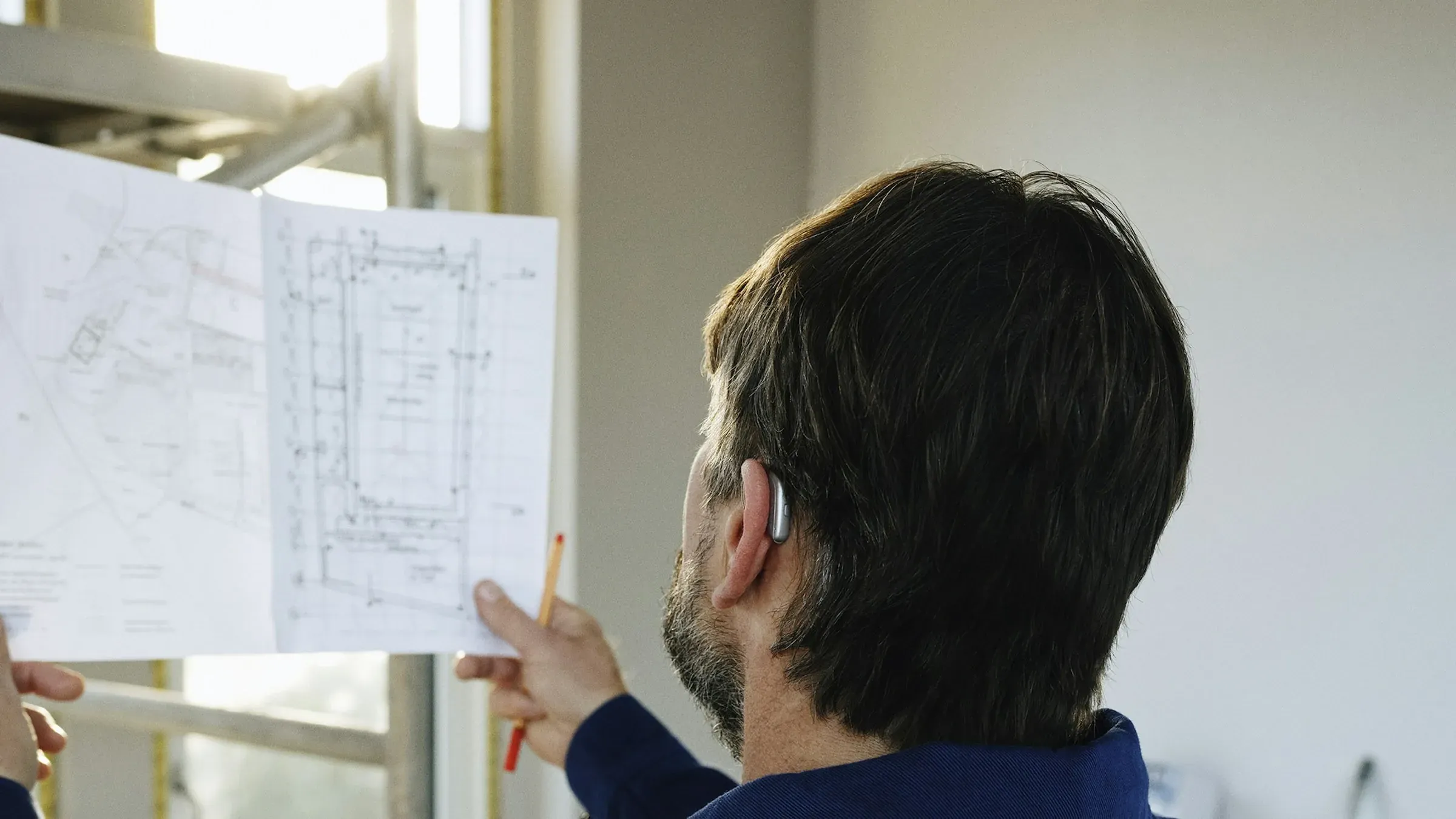 Builder holding up a drawing sheet to check it against the room under construction