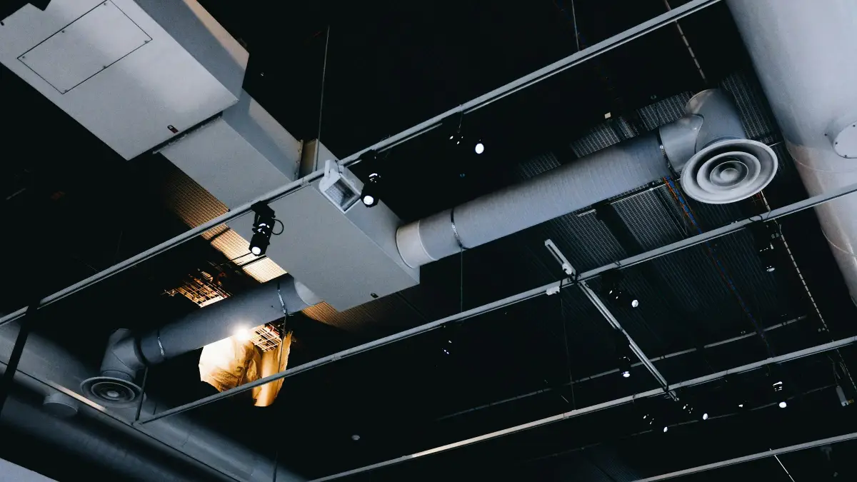 Grey ventilation ductwork and diffusers suspended from the ceiling of a commercial building