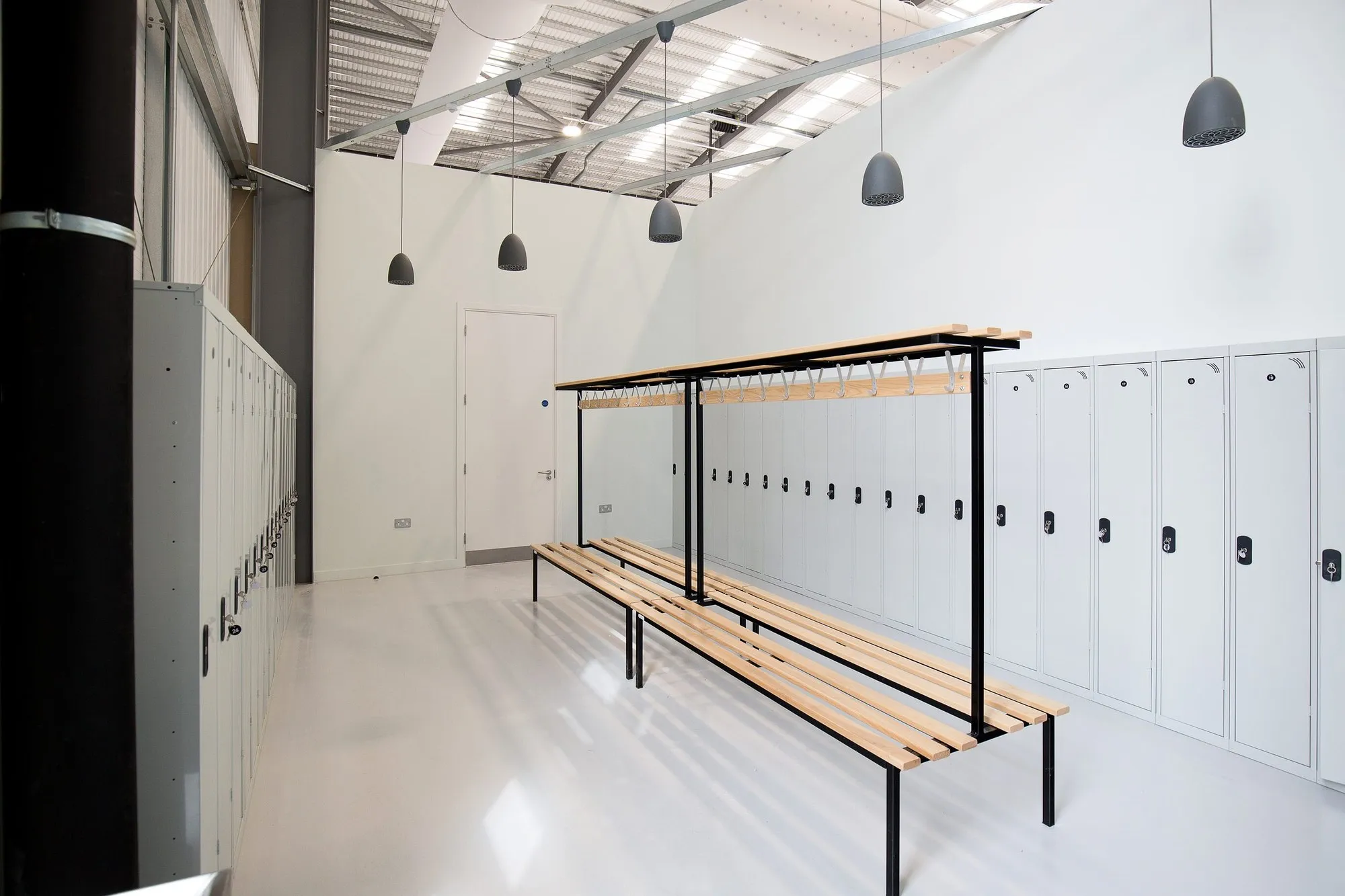 Changing room with lockers, a timber bench and pendant lights inside the Banbury warehouse