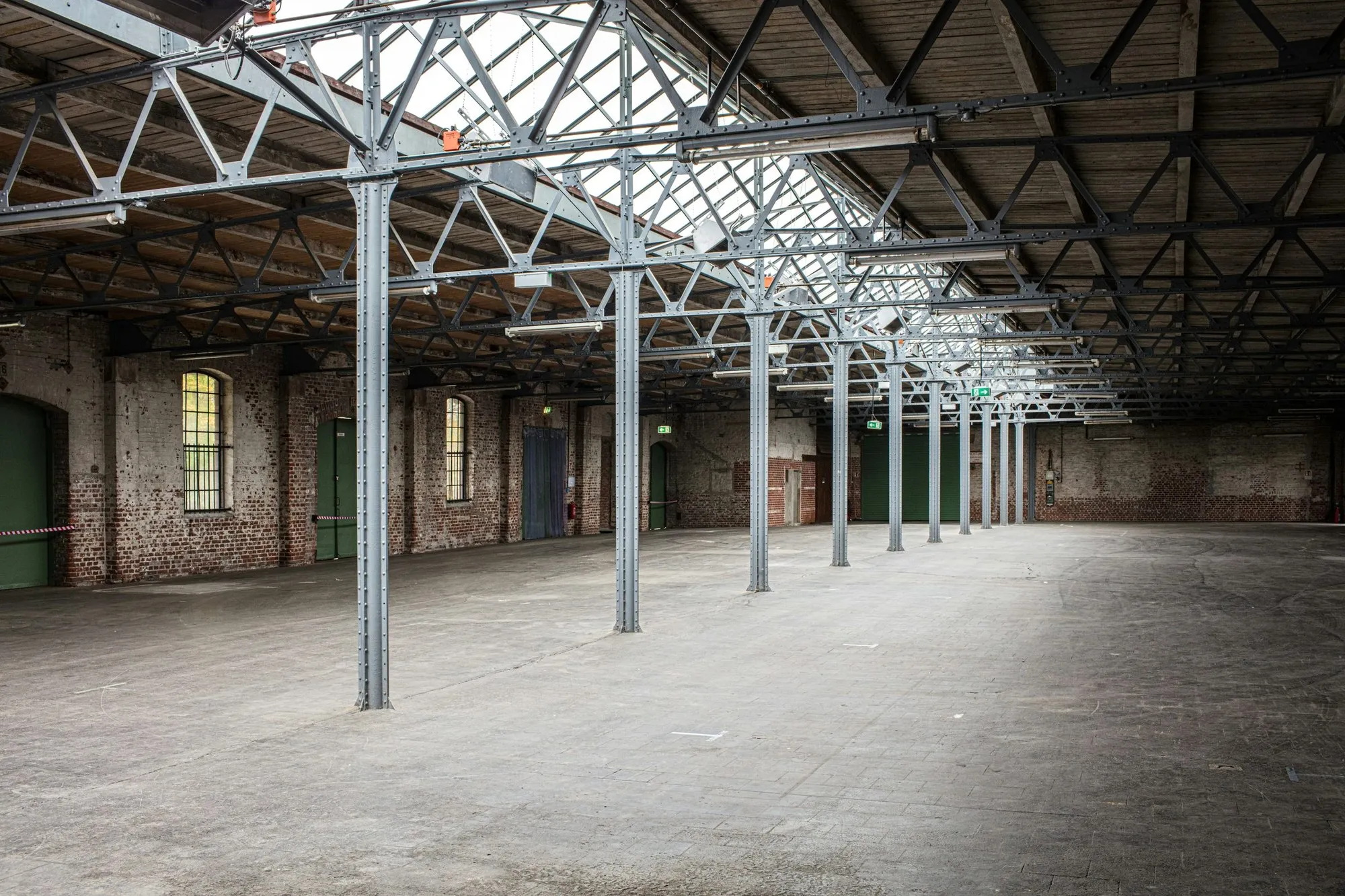 Refurbished warehouse hall with a steel frame, roof glazing and brick walls
