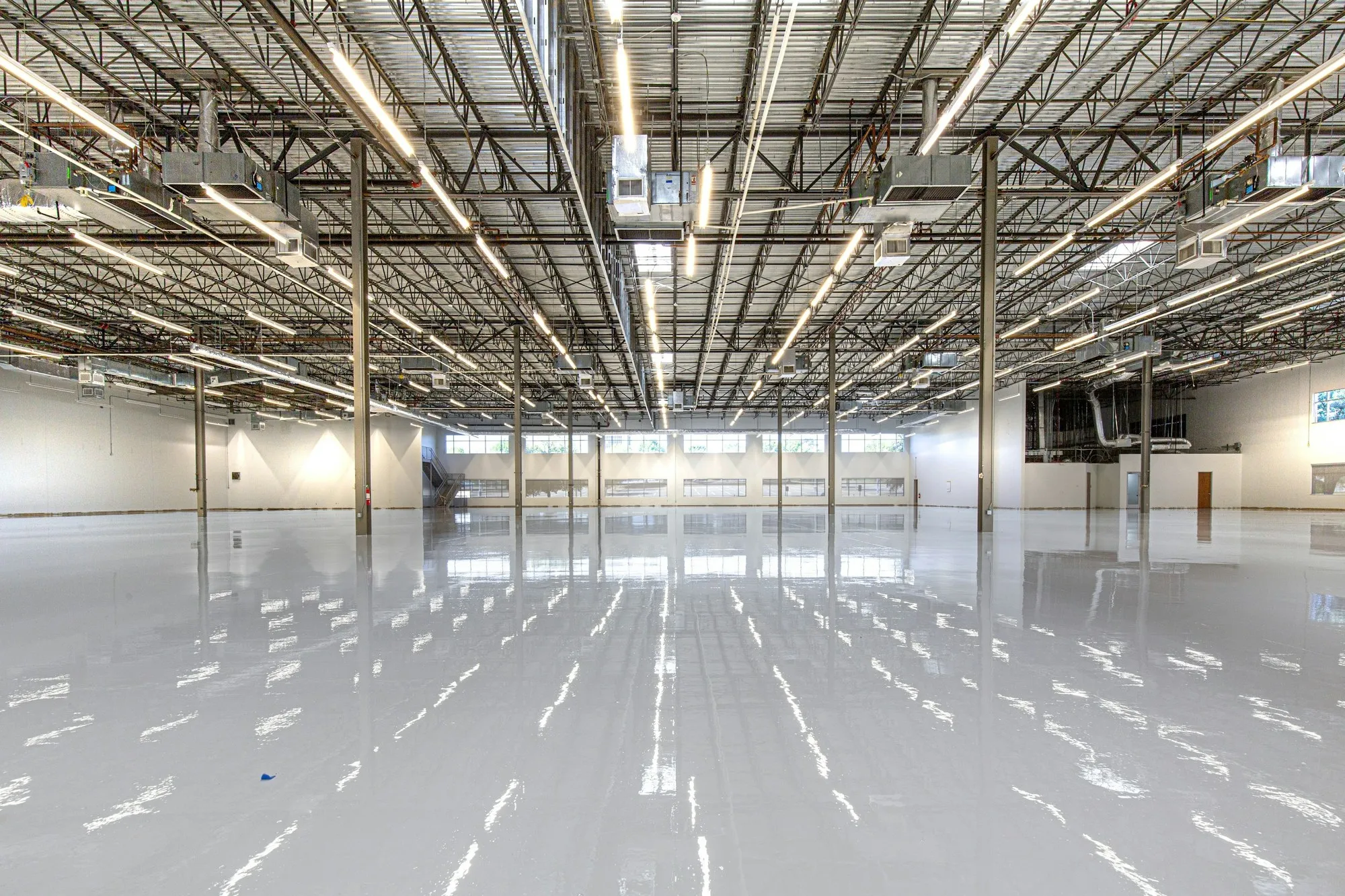Warehouse with rows of linear lights over a glossy resin floor