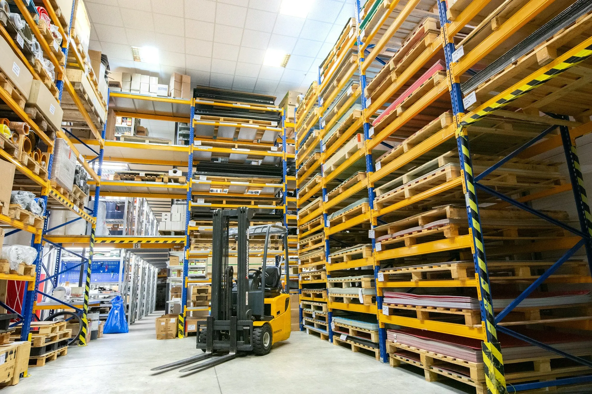 Narrow racking aisle with a forklift between orange pallet racks