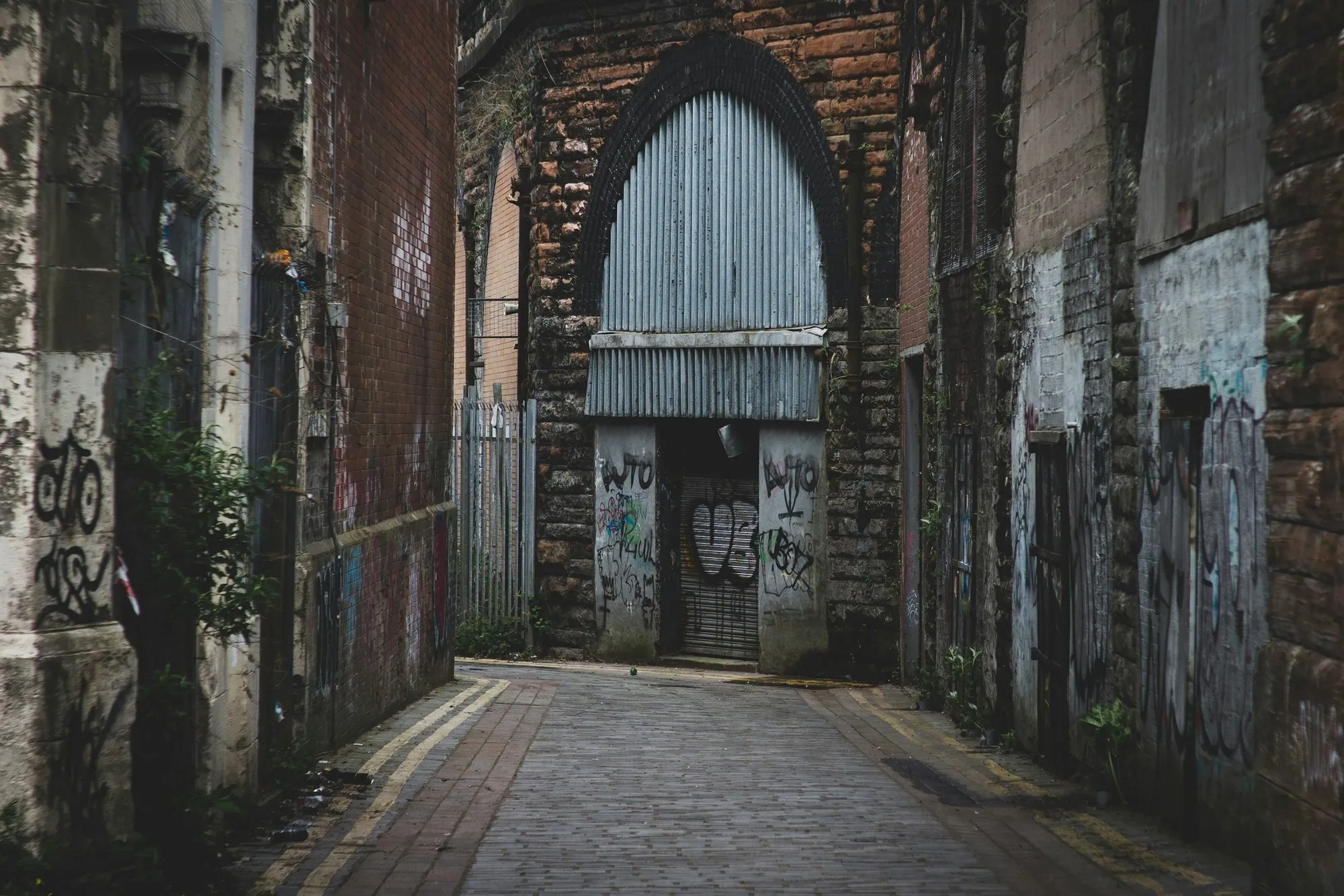 Glasgow lane with a weathered brick arch and a corrugated metal door