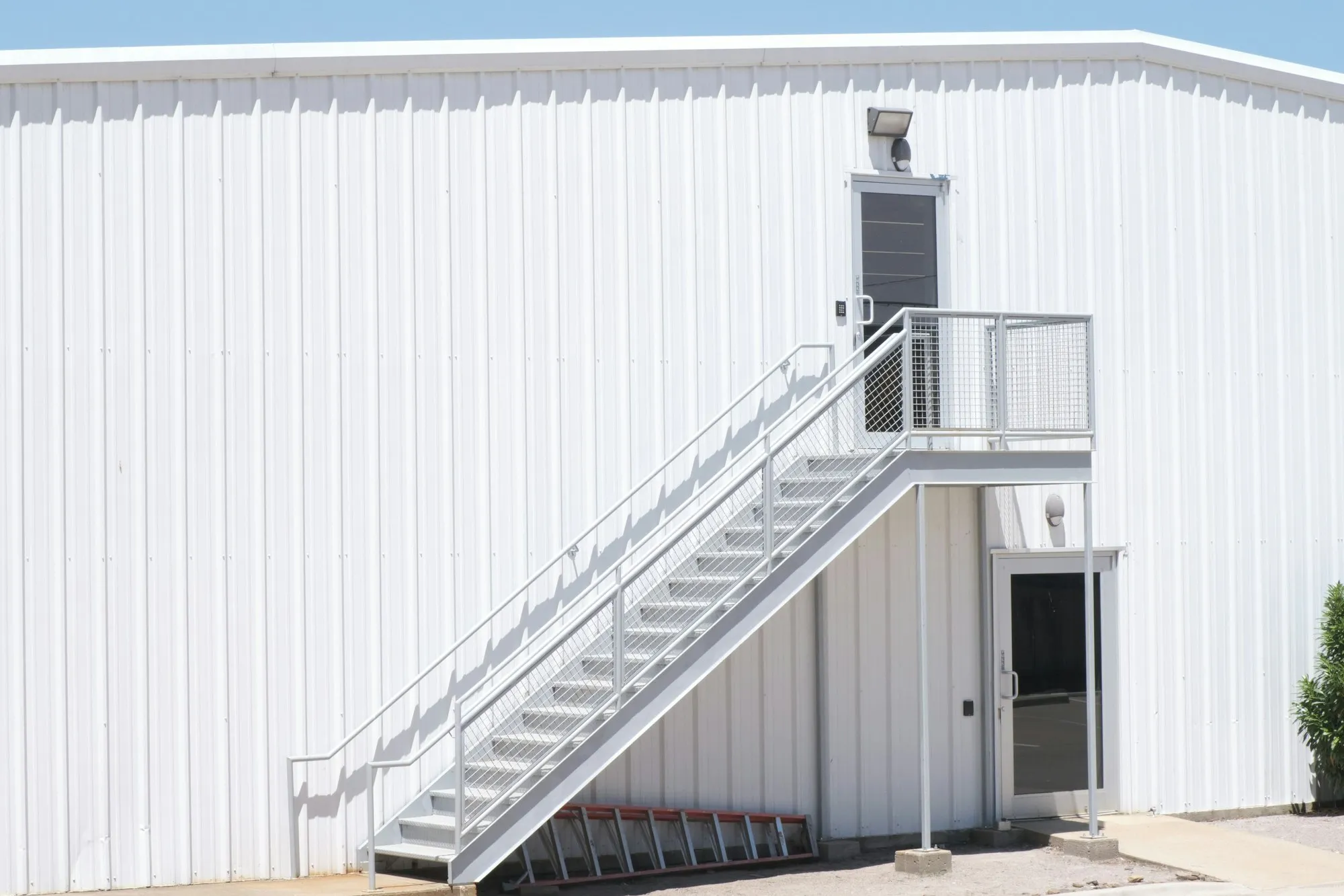 White steel-clad building with external steel staircase and guarding