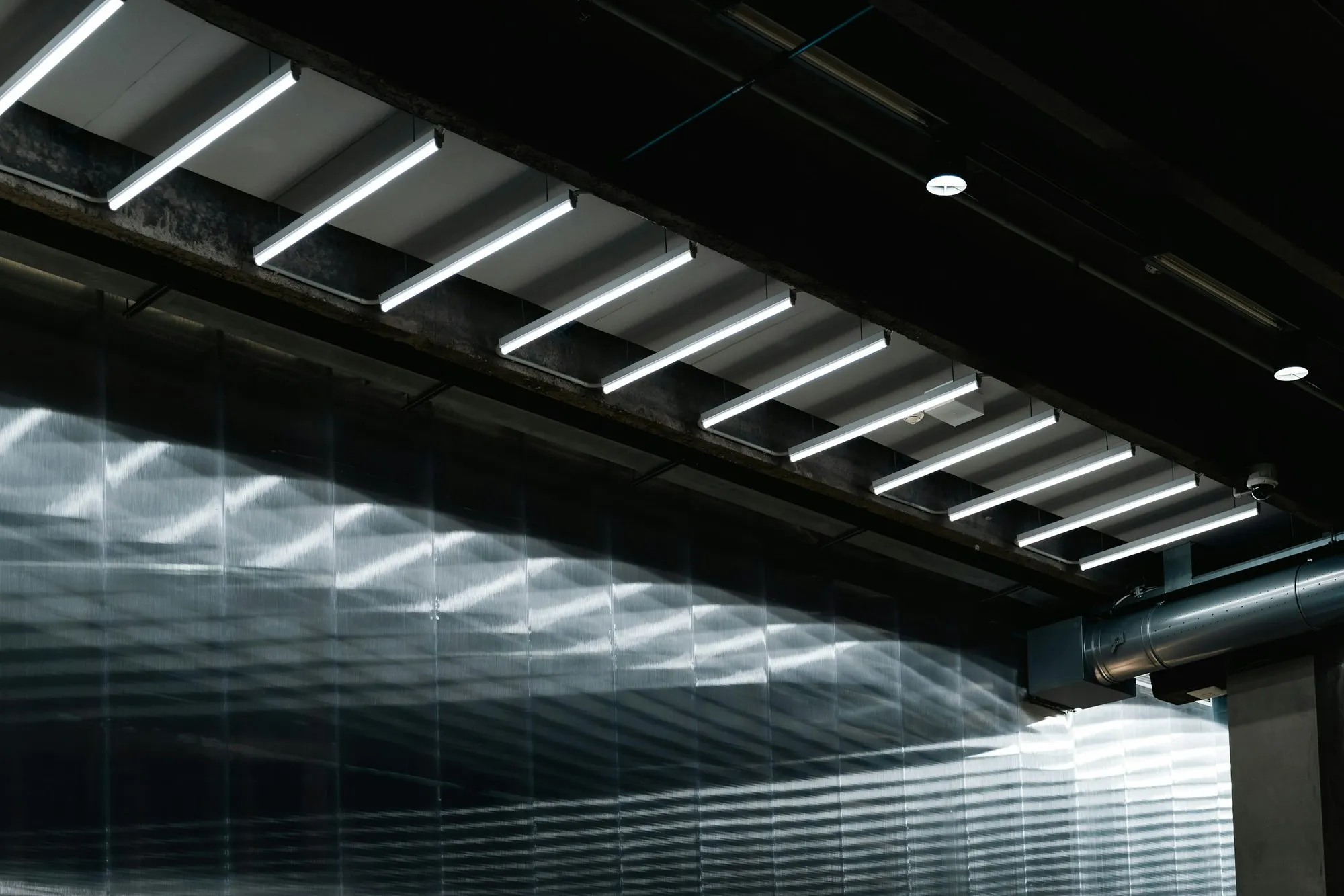 Rows of linear LED light fittings along a dark industrial ceiling