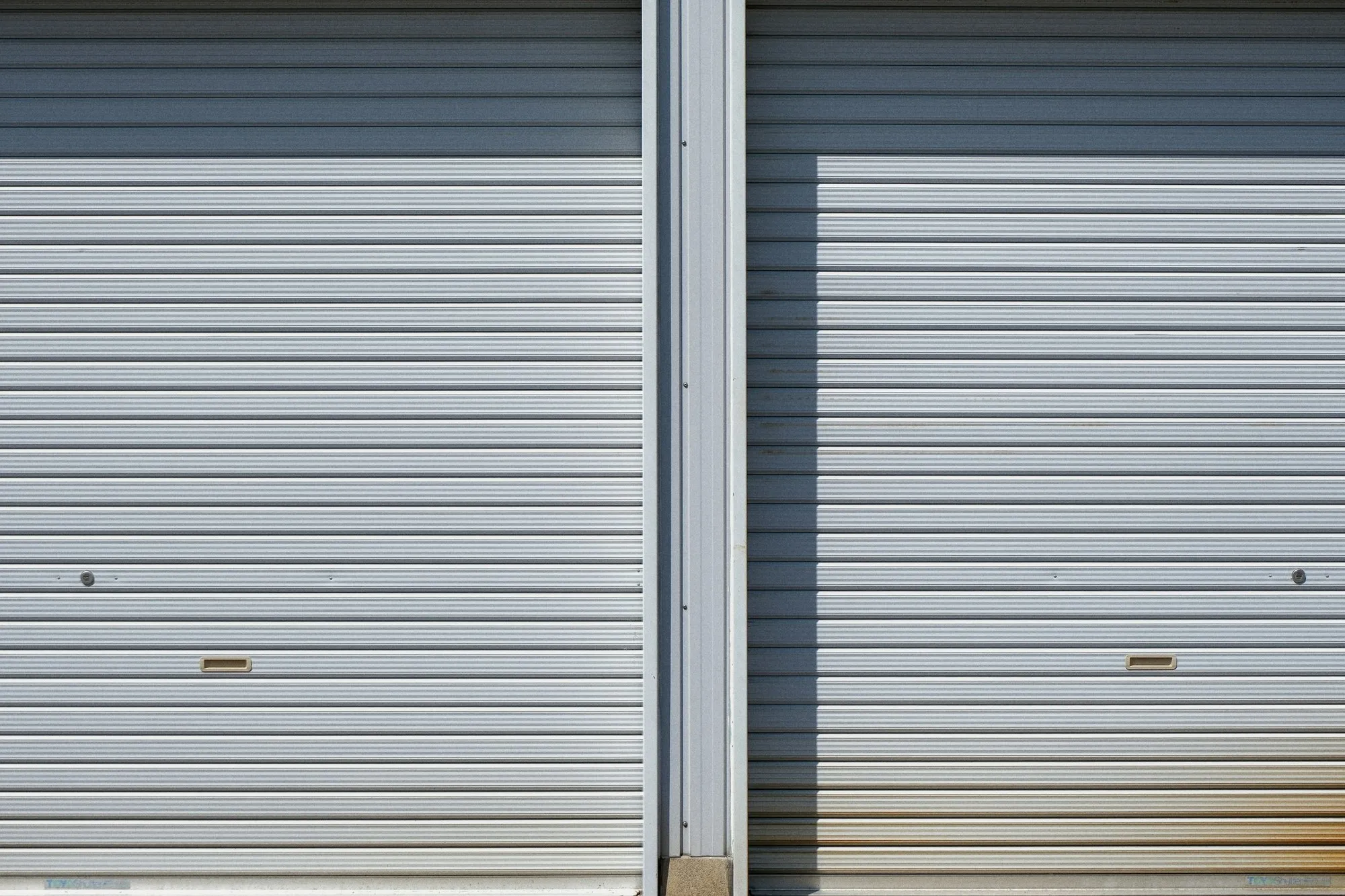 Two grey roller-shutter doors on an industrial unit